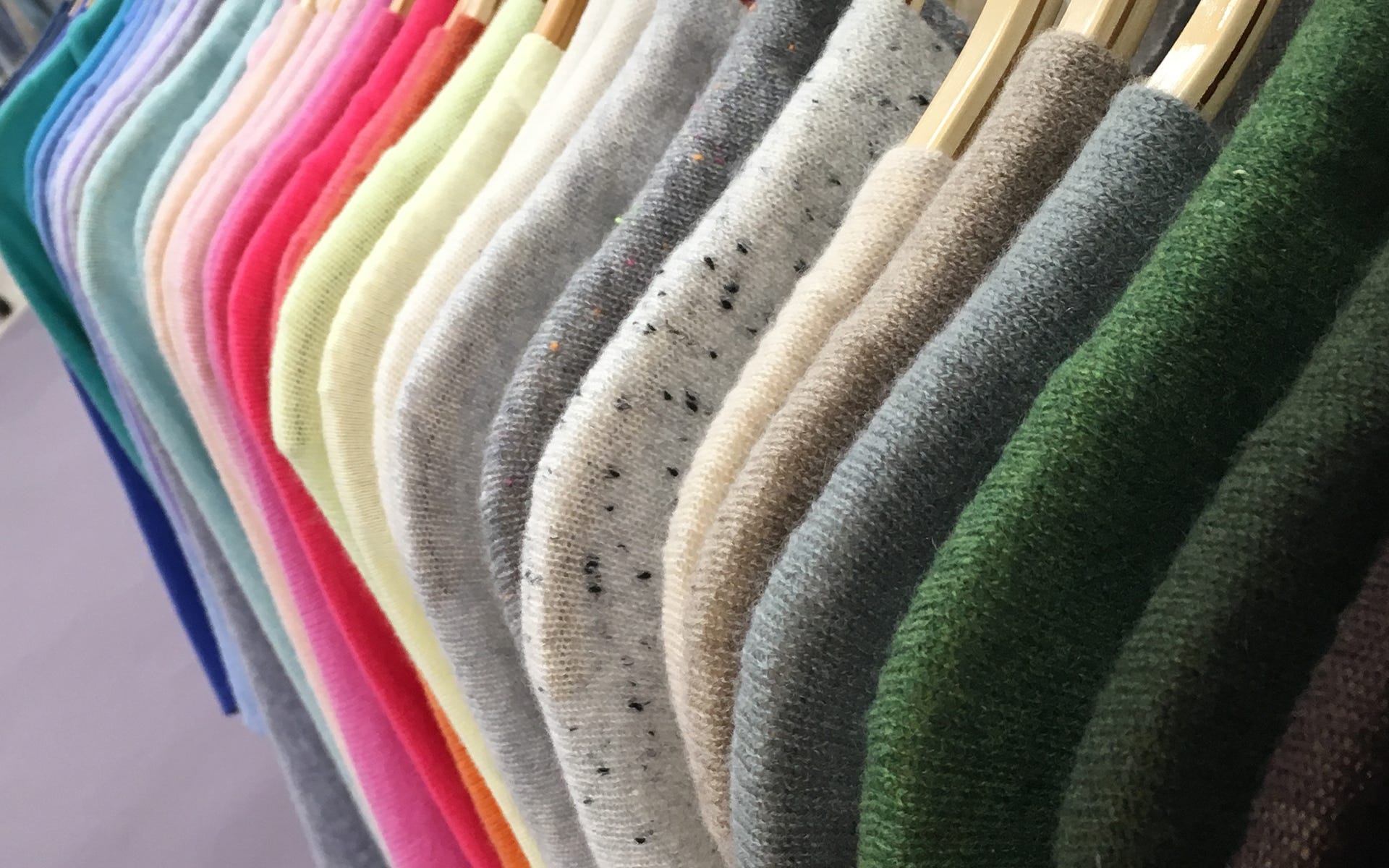 Alashan Cashmere sweaters in various colors on hangers.